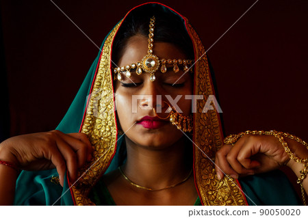 portrait indian beautiful female in golden rich jewelery and tradition saree face closeup professional make-up wearing bindi on head .Muslim Woman face portrait with bindis maang tikka ,nath,nose Pin portrait indian beautiful female in golden rich jewelery and tradition saree face closeup professional make-up wearing bindi on head .Muslim Woman face portrait with bindis maang tikka ,nath,nose Pin 90050020
