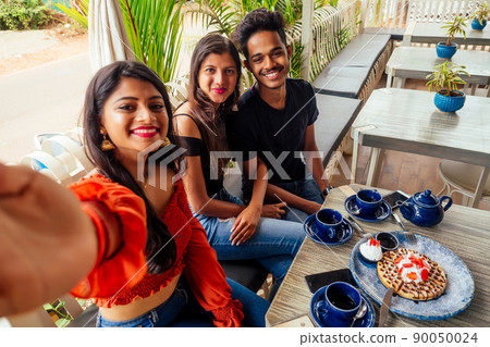 fashionable indian friends couple of two woman and man making selfie mobile phone.friends long-awaited meeting students eating pancake drinking masala tea after shopping.summer instahram lifestyle fashionable indian friends couple of two woman and man making selfie mobile phone.friends long-awaited meeting students eating pancake drinking masala tea after shopping.summer instahram lifestyle 90050024