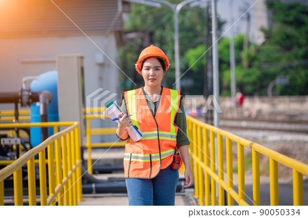 Worker wearing safety uniform under checking the waste water treatment pond industry ,she used radio communication to connect with another worker in large to control water support industry. Worker wearing safety uniform under checking the waste water treatment pond industry ,she used radio communication to connect with another worker in large to control water support industry. 90050334