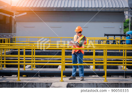 Worker wearing safety uniform under checking the waste water treatment pond industry ,she used radio communication to connect with another worker in large to control water support industry. Worker wearing safety uniform under checking the waste water treatment pond industry ,she used radio communication to connect with another worker in large to control water support industry. 90050335
