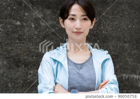 A woman in sportswear leaning against a wall 90050758