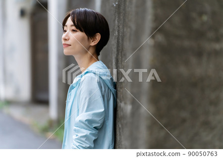 A woman in sportswear leaning against a wall 90050763