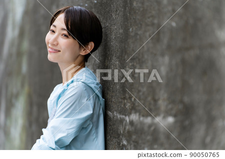 A woman in sportswear leaning against a wall 90050765