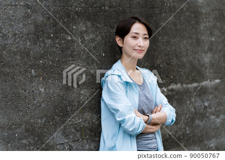 A woman in sportswear leaning against a wall 90050767