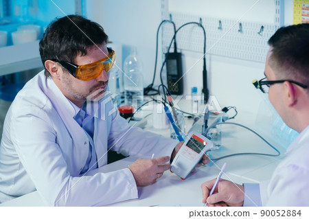 Portrait of a scientist working in the lab examines a test tube with liquid. Portrait of a scientist working in the lab examines a test tube with liquid. 90052884