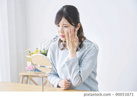 A woman in trouble looking at her face in the mirror in the living room 90053871