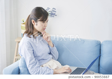 A woman looking at a laptop in the living room A woman looking at a laptop in the living room 90053887