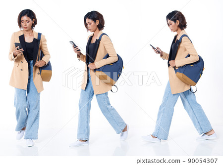 Full length of Asian Indian 20s working woman with curl hair hold cell smart phone backpack blazzer 90054307