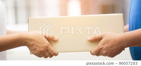 parcel delivery man of a package through a service. and close up hand customer female accepting a delivery of boxes from delivery man postal send direct to home. 90057283