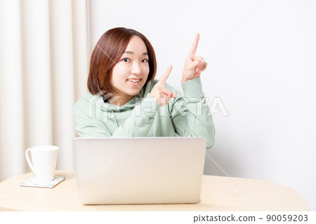 A woman pointing to a point while using a computer A woman pointing to a point while using a computer 90059203