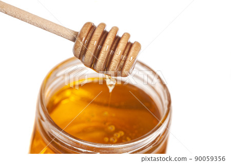 Honey dripping from honey dipper in glass jar. Healthy food concept Honey dripping from honey dipper in glass jar. Healthy food concept 90059356
