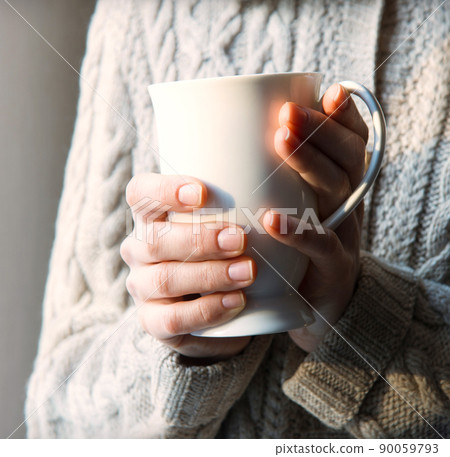 Women's hands holding a warm cup 90059793