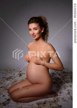 A young white pregnant woman is nine months pregnant on a bright background A young white pregnant woman is nine months pregnant on a bright background 90060219
