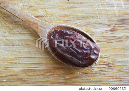 Organic dried hurma dates medjool grains, in wooden spoon on cutting board 90060685
