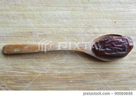 Organic dried hurma dates medjool grains, in wooden spoon on cutting board 90060686