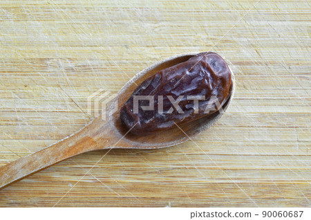 Organic dried hurma dates medjool grains, in wooden spoon on cutting board Organic dried hurma dates medjool grains, in wooden spoon on cutting board 90060687