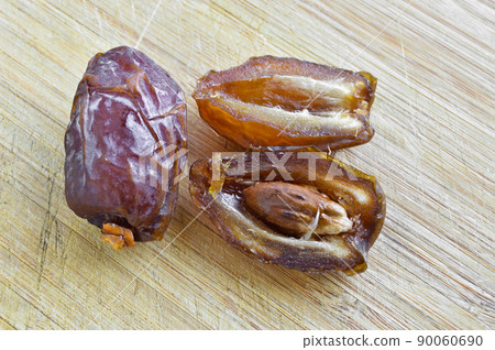 Organic fresh nutritious dried hurma dates medjool grains, on cutting board Organic fresh nutritious dried hurma dates medjool grains, on cutting board 90060690