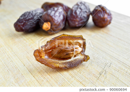 Organic fresh nutritious dried hurma dates medjool grains, on cutting board Organic fresh nutritious dried hurma dates medjool grains, on cutting board 90060694
