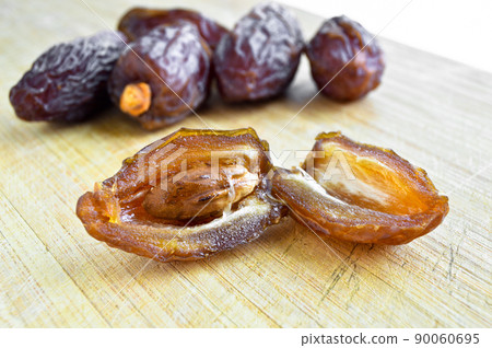 Organic fresh nutritious dried hurma dates medjool grains, on cutting board Organic fresh nutritious dried hurma dates medjool grains, on cutting board 90060695