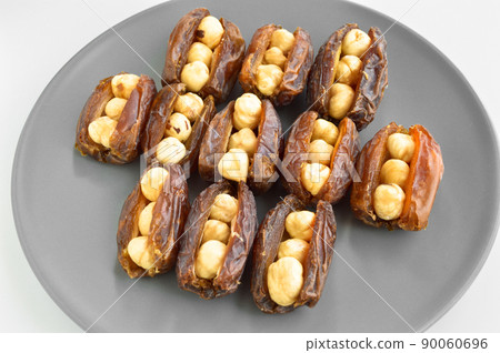Dried hurma dates medjool grains, hazelnuts placed inside the date, in a gray plate Dried hurma dates medjool grains, hazelnuts placed inside the date, in a gray plate 90060696