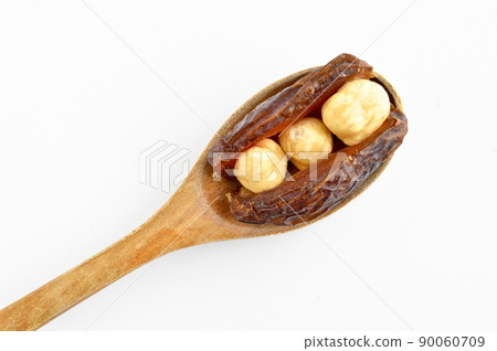 Dried hurma dates medjool grains, hazelnuts placed inside the date, on wooden spoon 90060709