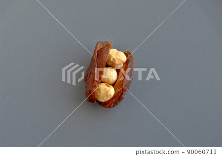 Dried hurma dates medjool grains, hazelnuts placed inside the date, in a gray plate Dried hurma dates medjool grains, hazelnuts placed inside the date, in a gray plate 90060711