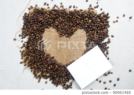 Close-up view of coffee beans with heart shape on sackcloth with empty paper 90061488