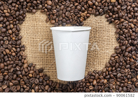 Close up view of coffee beans with heart shape and white plastic cup Close up view of coffee beans with heart shape and white plastic cup 90061582