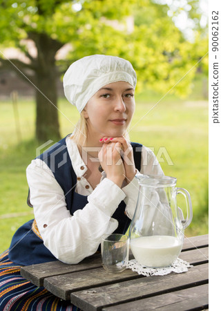 Latvian woman in traditional clothing with milk glass on nature Latvian woman in traditional clothing with milk glass on nature 90062162