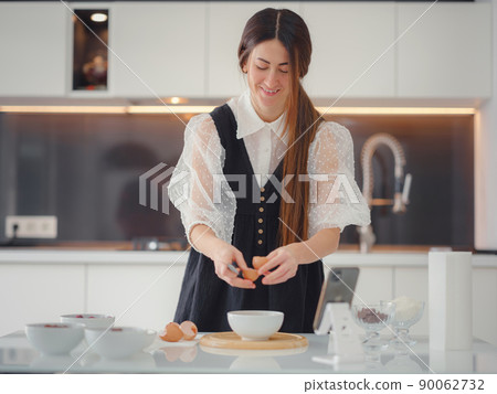 Beautiful young woman smiling while baking in kitchen at home 90062732
