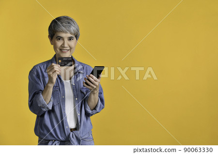 Portrait of middle aged Asian woman holding smartphone and credit card shopping online Portrait of middle aged Asian woman holding smartphone and credit card shopping online 90063330