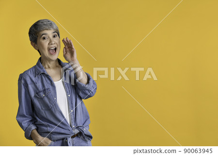 Middle aged Asian woman 50s is holding hand near mouth and telling a secret isolated Middle aged Asian woman 50s is holding hand near mouth and telling a secret isolated 90063945