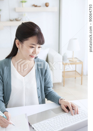 A woman who operates a personal computer at home 90064793