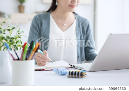 A woman who operates a personal computer at home 90064880