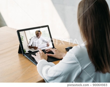 Video call. Remote work. Digital meeting. Business woman using laptop discussing project online with male partner on screen in virtual home office. 90064983