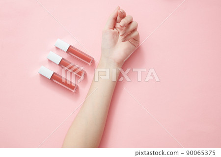 Top view of hand model holding lipstick in pink background for cosmetic advertising 90065375