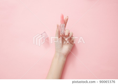Top view of hand model holding lipstick in pink background for cosmetic advertising Top view of hand model holding lipstick in pink background for cosmetic advertising 90065376
