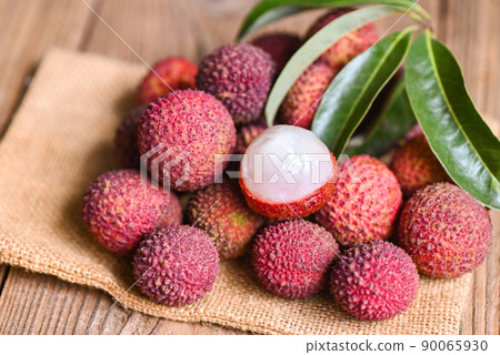 Lychee fruit on sack with green leaf and wooden background, fresh ripe lychee peeled from lychee tree at tropical fruit Thailand in summer 90065930