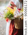 A woman with a basket full of flowers 90066172