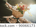 A woman who rides with flowers in the basket of a bicycle 90066173