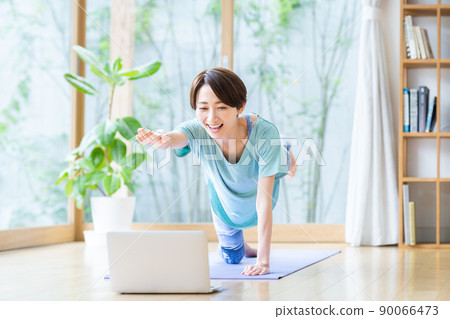 Middle-aged woman doing online yoga at home Middle-aged woman doing online yoga at home 90066473