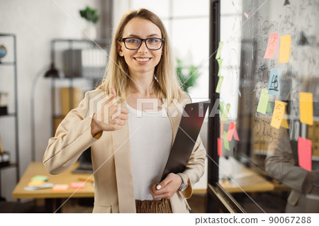 Business lady holding clipboard and smiling at office 90067288