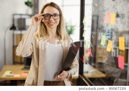 Business lady holding clipboard and smiling at office Business lady holding clipboard and smiling at office 90067289