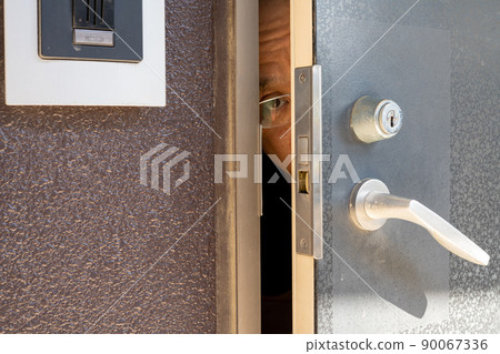 A man peeking through the front door A man peeking through the front door 90067336