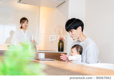 Daddy using a computer with a baby Daddy using a computer with a baby 90067662