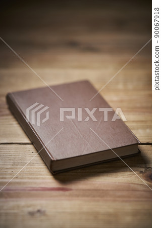 一本放在舊桌子上的棕色封面書 90067918