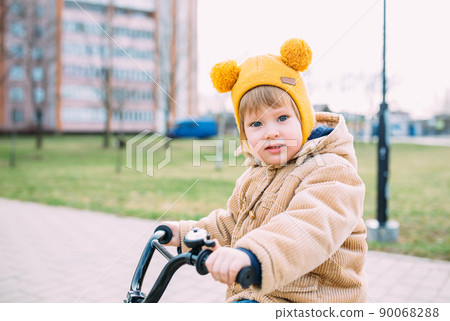 A small child learns to ride a bike for the first time in the city in spring 90068288