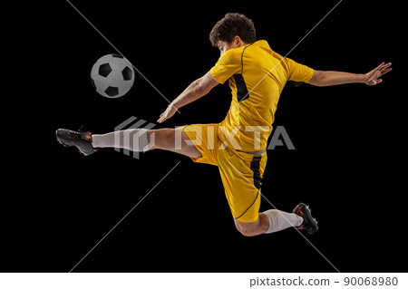 Dynamic portrait of professional football, soccer player training with ball isolated on dark background. Concept of sport, match, active lifestyle, goal and hobby Dynamic portrait of professional football, soccer player training with ball isolated on dark background. Concept of sport, match, active lifestyle, goal and hobby 90068980