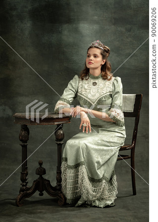 Vintage portrait of young beautiful girl in gray dress of medieval style isolated on dark background. Comparison of eras concept, flemish style. Art, beauty 90069206