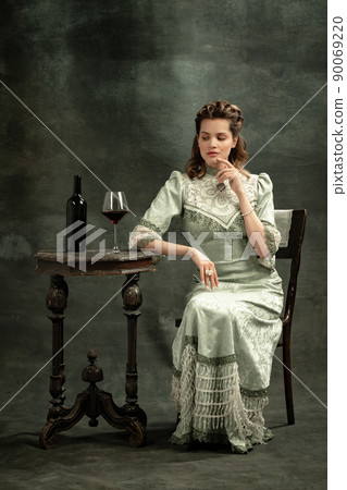 Vintage portrait of young beautiful girl in gray dress of medieval style isolated on dark background. Comparison of eras concept, flemish style. Art, beauty 90069220